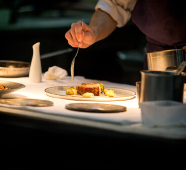 Chef,Preparing,A,Dish,With,Meat,On,A,Plate,Under